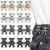 A collection of adjustable bear button pins in gold and silver colors displayed on a denim fabric.
