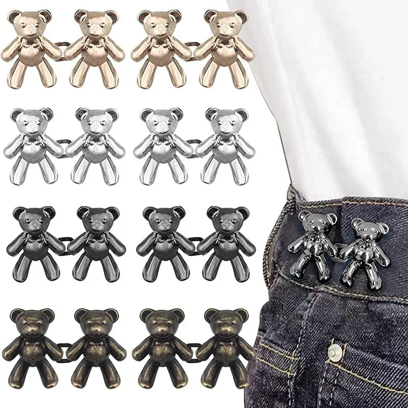 A collection of adjustable bear button pins in gold and silver colors displayed on a denim fabric.