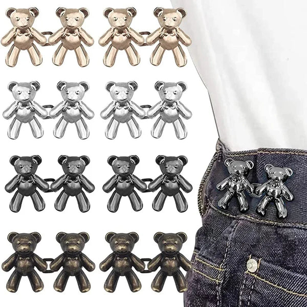 A collection of adjustable bear button pins in gold and silver colors displayed on a denim fabric.
