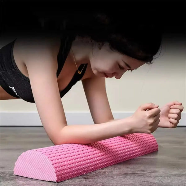 A person is using a pink massage foam roller for yoga and fitness exercises.