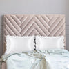 A beige upholstered headboard with a quilted pattern and two white satin pillowcases.
