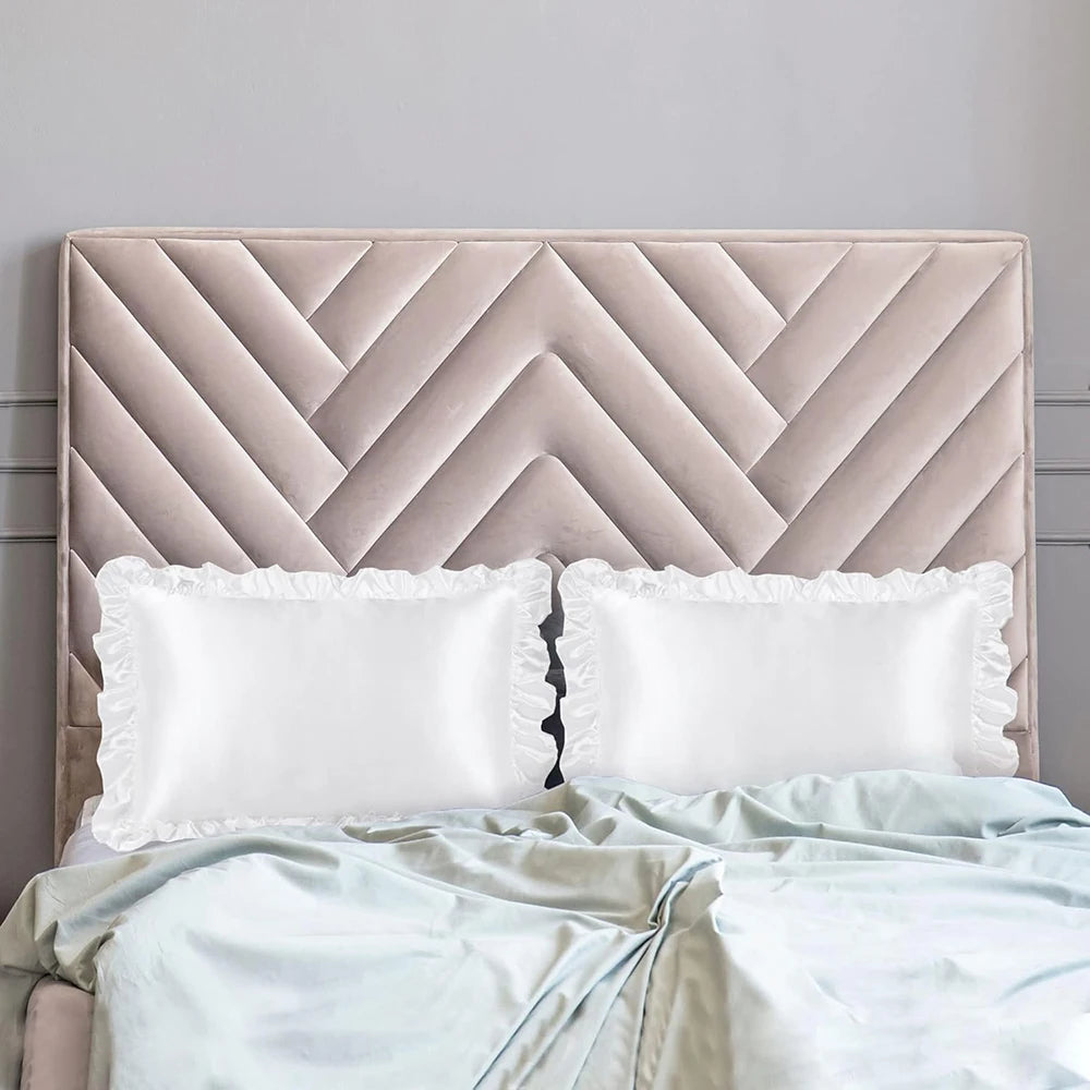 A beige upholstered headboard with a quilted pattern and two white satin pillowcases.