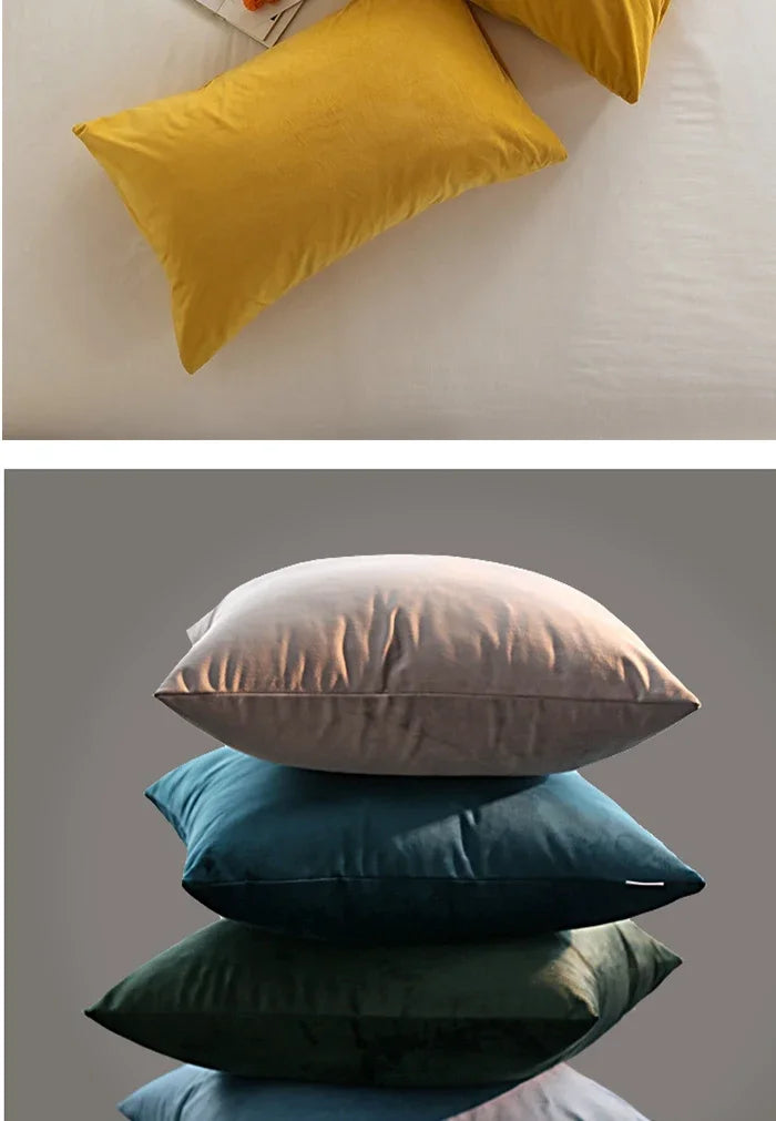 A stack of velvet throw pillows in shades of yellow, beige, teal, and dark green.
