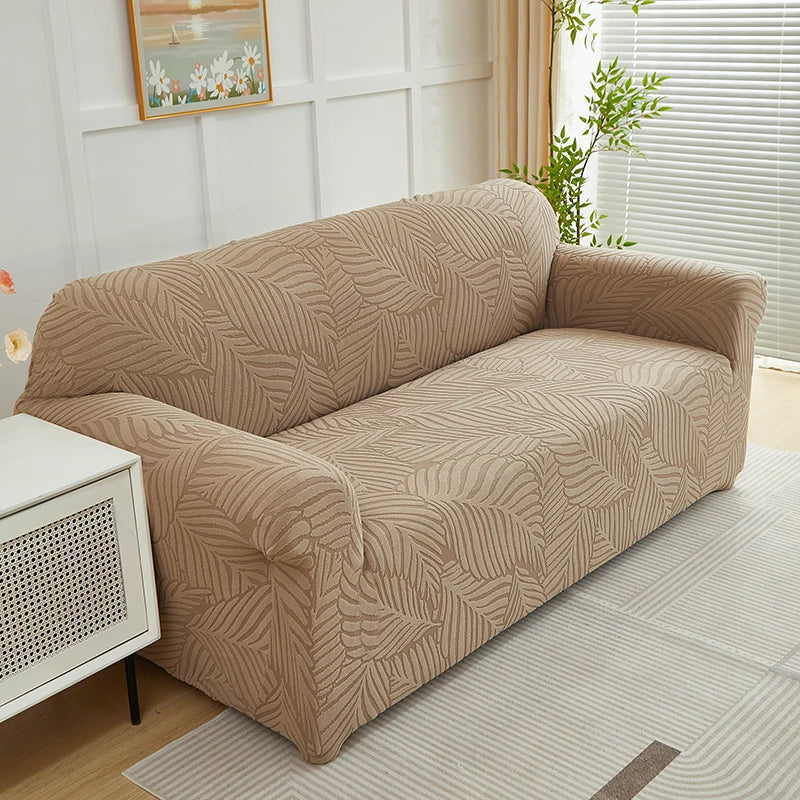 A beige sofa slipcover featuring a jacquard leaves pattern, placed in a bright room.
