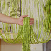 A hand is holding long, shimmering lime green decorative door string curtains that drape down like a curtain.