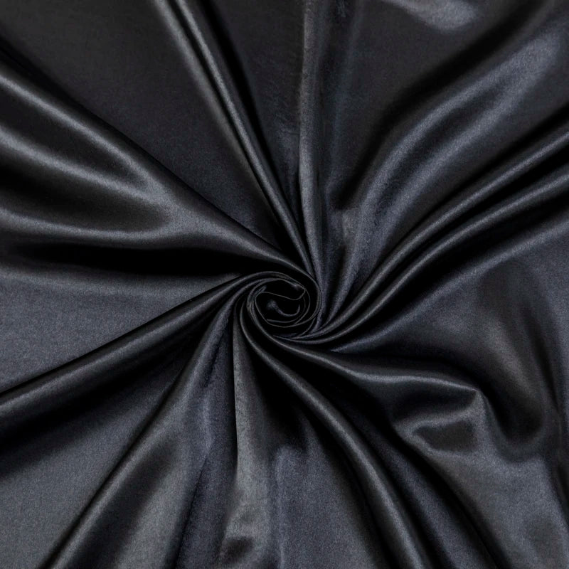 Black satin luxury bedding fabric tightly rolled to show its smooth texture and sheen.