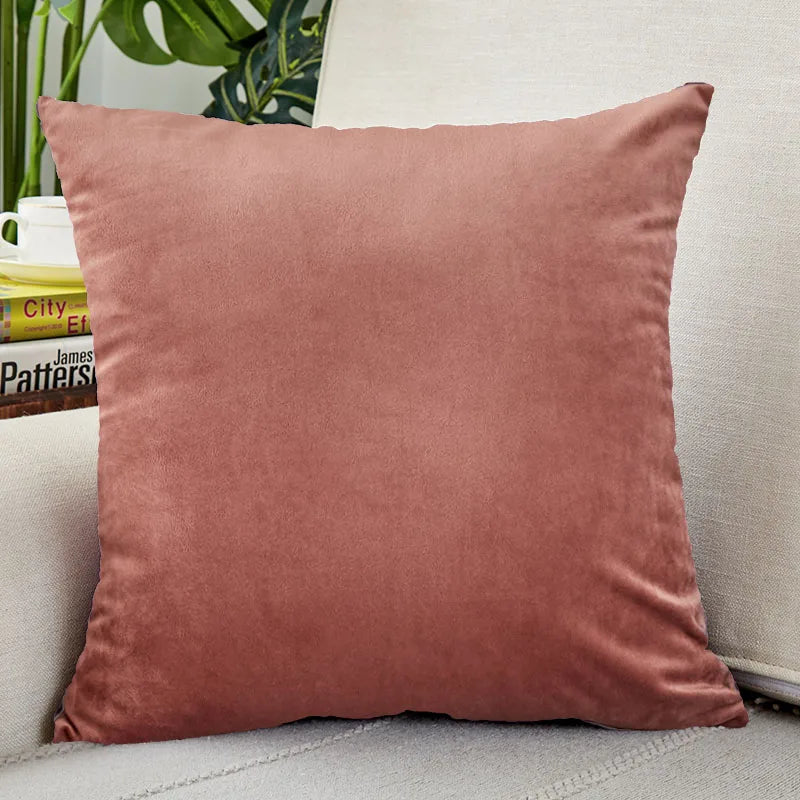 A square, dusty rose velvet cushion cover resting on a light-colored sofa.