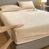 A close-up of beige luxury velvet bedding, including a sheet and pillow, resting on a bed.