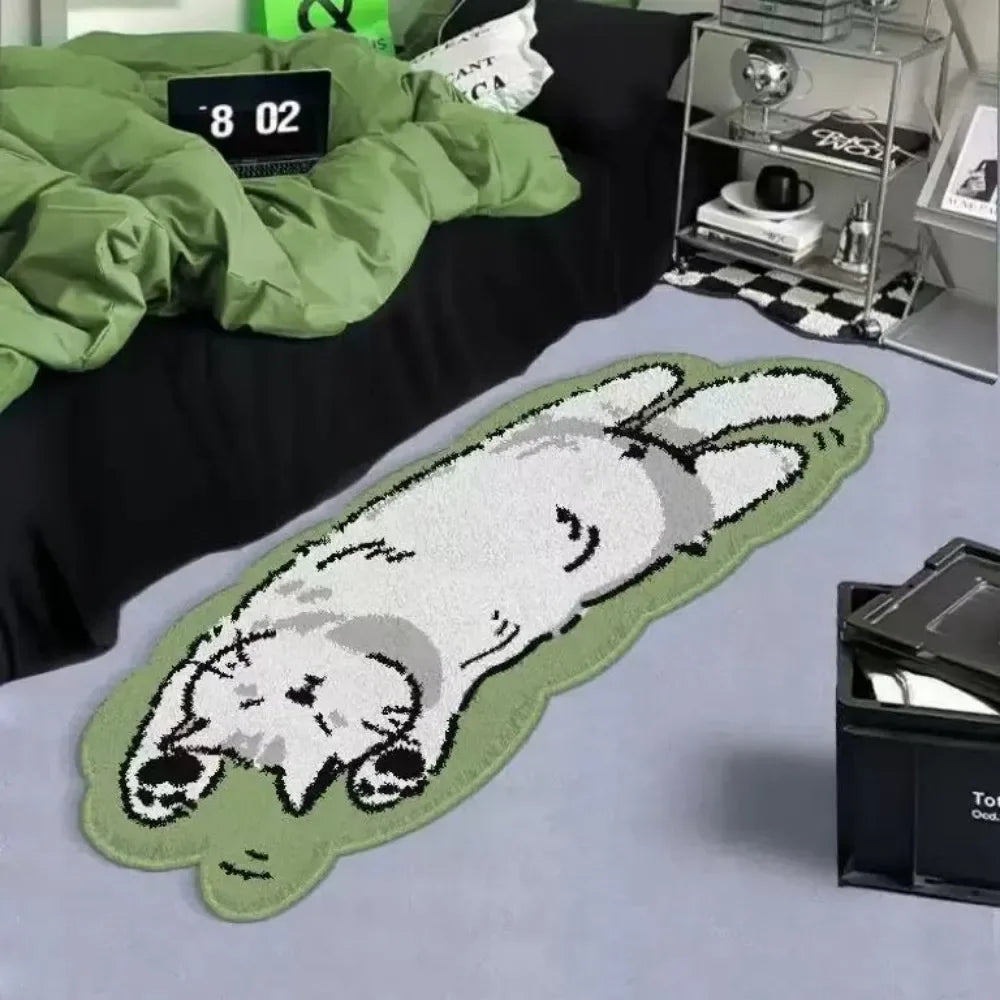 A light green cartoon cat plush rug is displayed on a gray surface next to a black fabric and some glass items.
