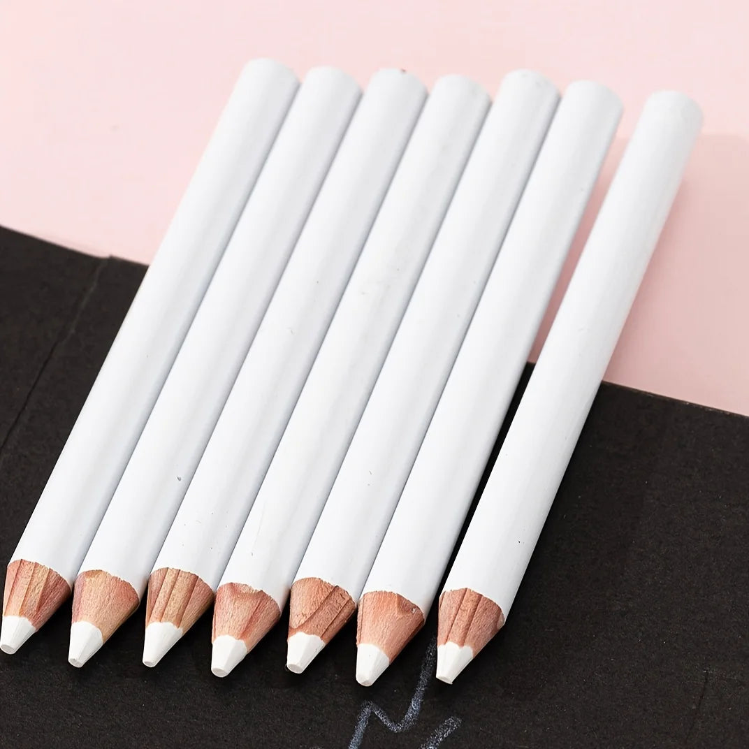 A set of white chalk pencils with natural wood accents are arranged diagonally on a black surface.