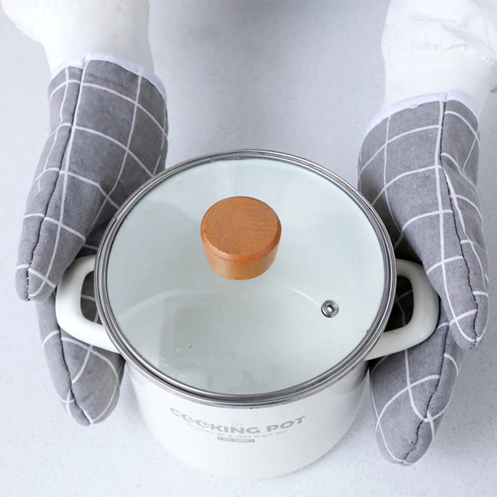 A pair of white heat-resistant kitchen oven gloves with gray checkered fabric are holding a white cooking pot.