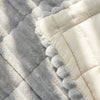 A close-up of a thick gray flannel sofa pad cover with white piping and fluffy trim.