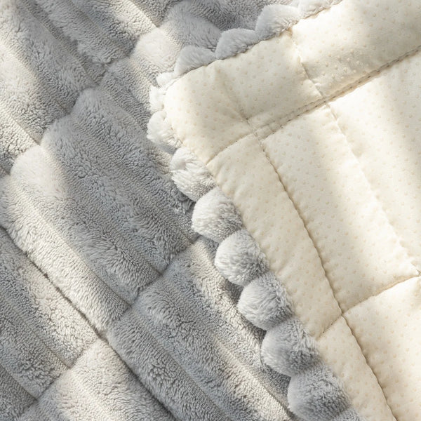 A close-up of a thick gray flannel sofa pad cover with white piping and fluffy trim.