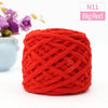 A ball of bright red chunky velvet knitting yarn with an intricate woven texture.