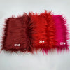 A swatch of faux fur fabric showing a gradient of colors including deep red, orange-red, and magenta.