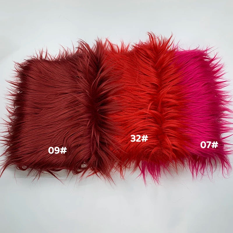 A swatch of faux fur fabric showing a gradient of colors including deep red, orange-red, and magenta.