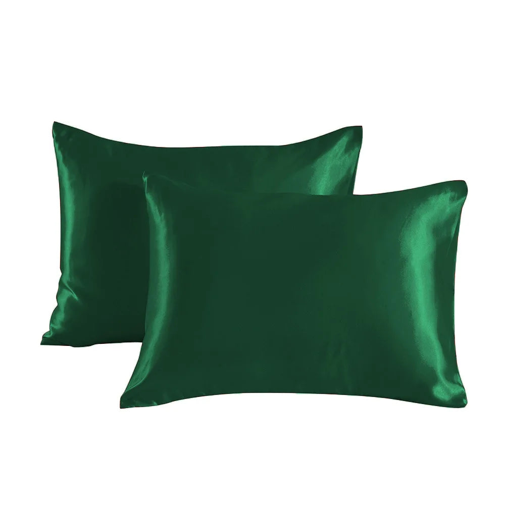 A pair of emerald green satin pillowcases lying flat.