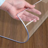 A hand is holding a clear PVC table protector mat, showing its flexible and transparent material.