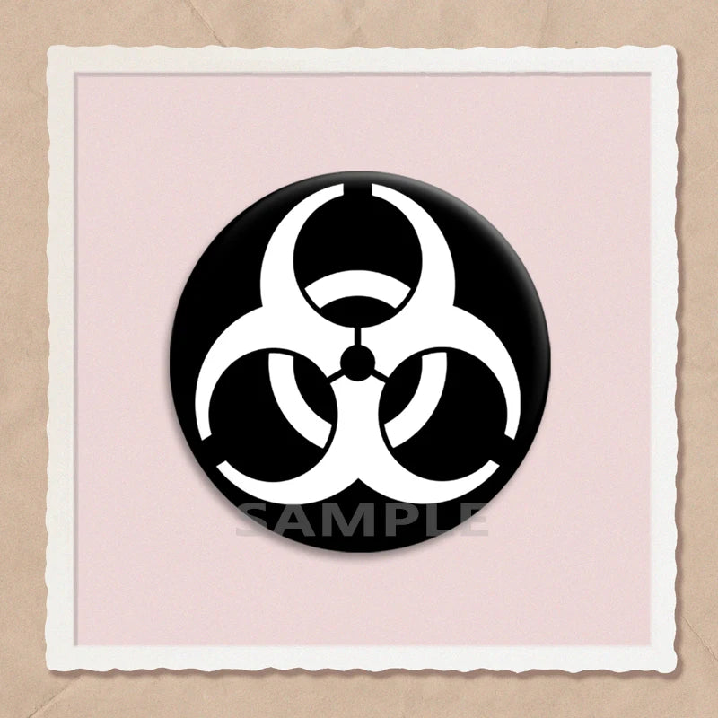 A black circular brooch pin featuring a white biohazard symbol on a light pink background.