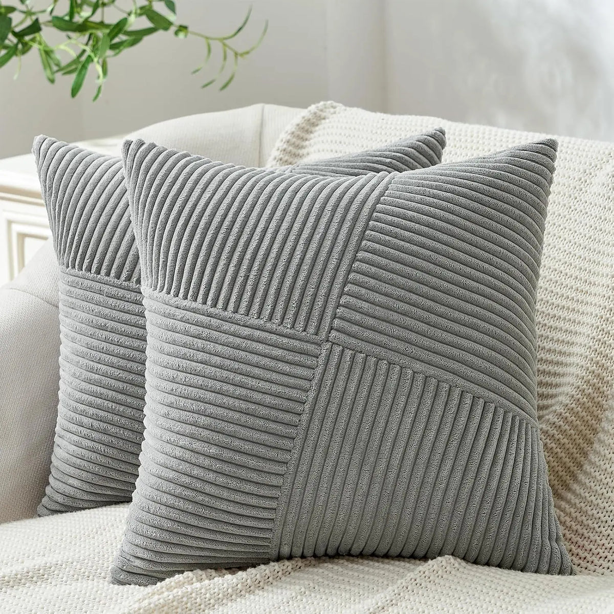 A single gray textured corduroy throw pillow cover with vertical ribbing resting on a cream-colored fabric.