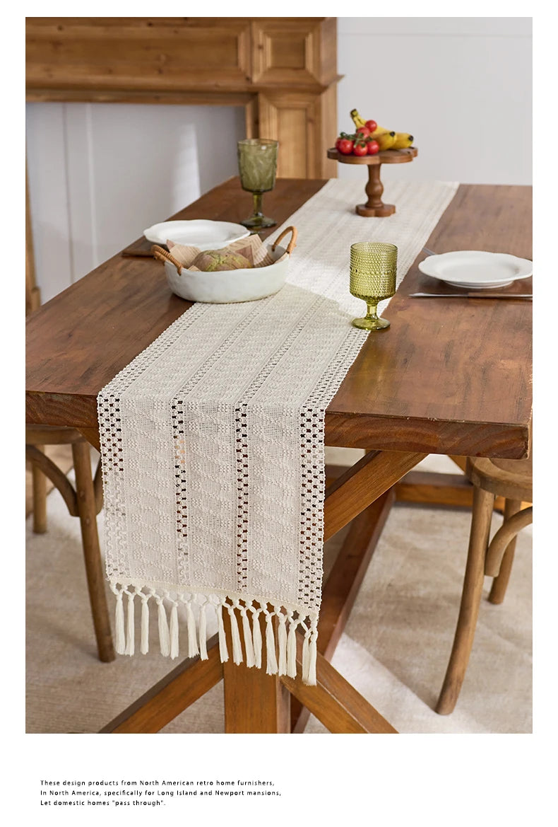 A beige hand-woven table runner is placed on a dark wooden table in a rustic home setting.