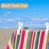 Close-up of colorful striped beach towel clips attached to a fabric, set against a blue sky and sandy background.