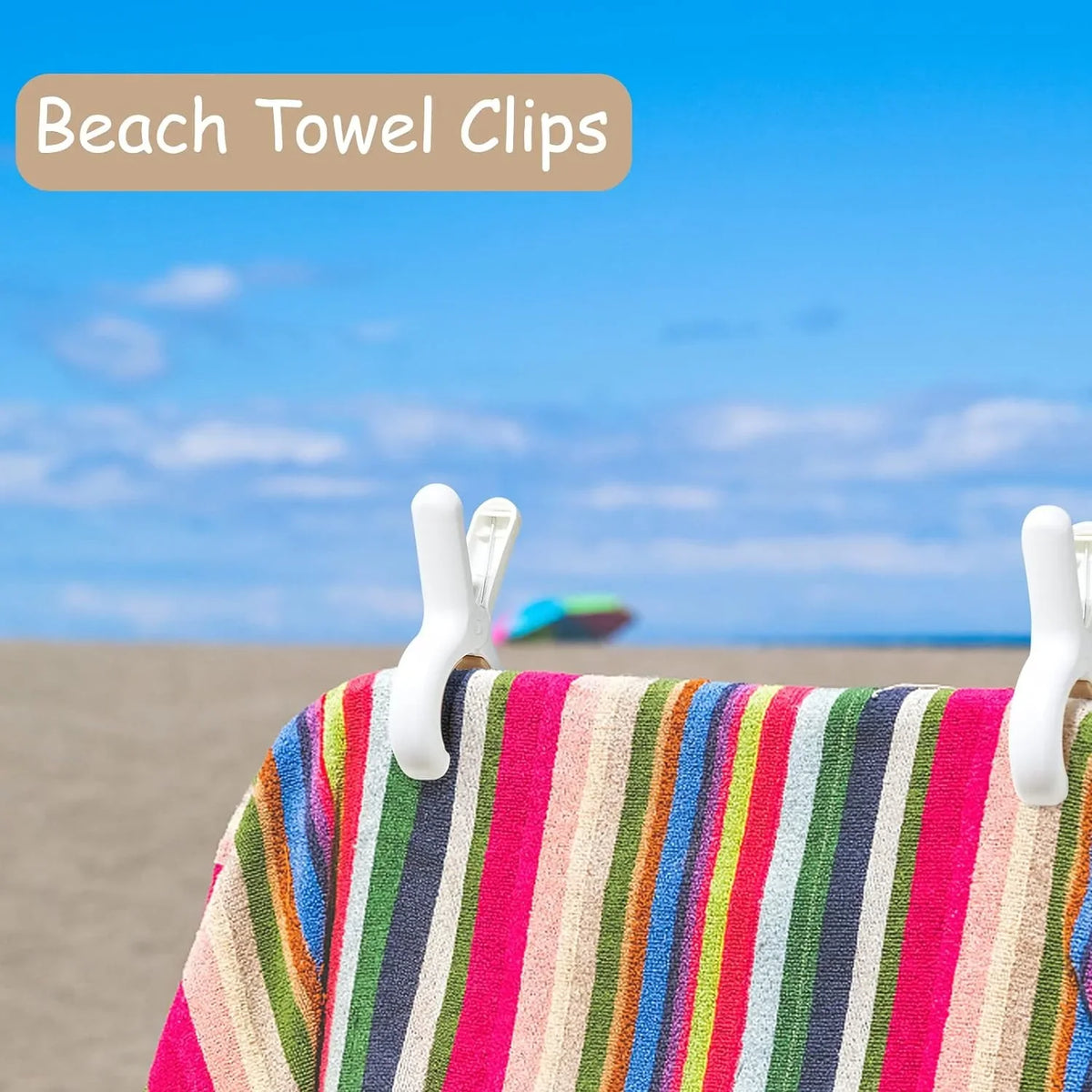 Close-up of colorful striped beach towel clips attached to a fabric, set against a blue sky and sandy background.