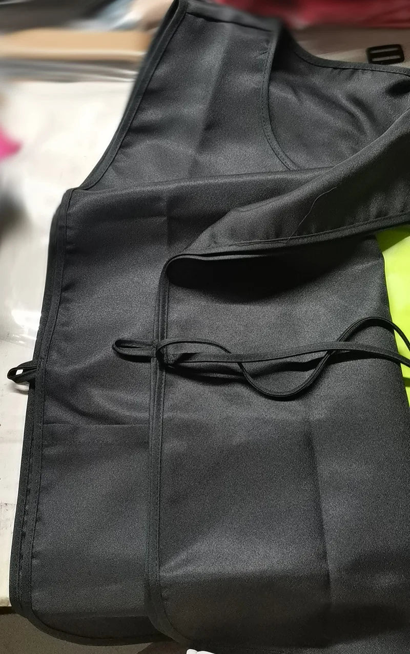 A black polyester apron is shown folded or hanging, featuring a drawstring closure.