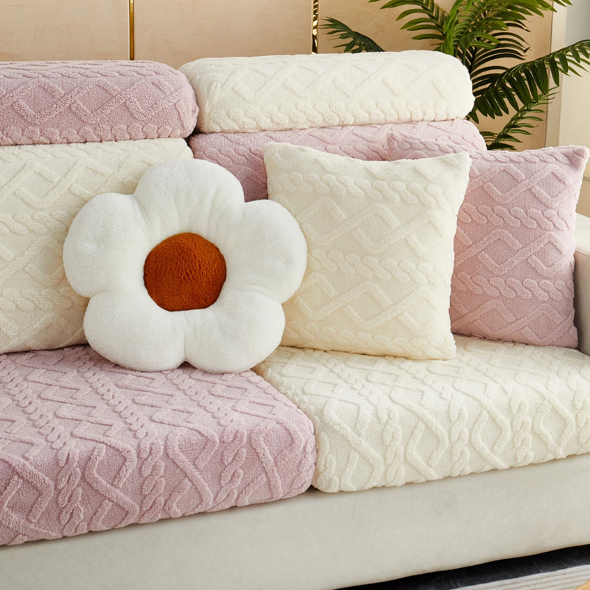 A collection of pink and cream textured throw pillows on a sofa.