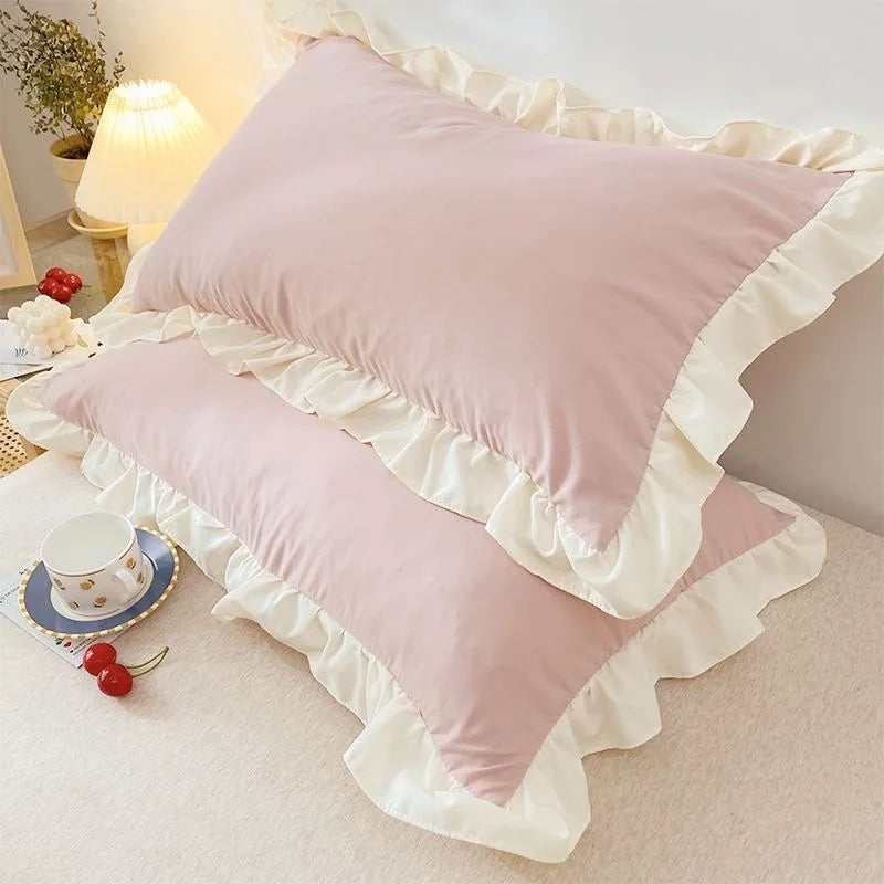 Pink ruffled pillowcases with a white trim and hidden zipper, displayed on a light-colored surface.