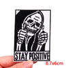 Black and white embroidery patch featuring a skull with hands raised, with the text STAY POSITIVE below.