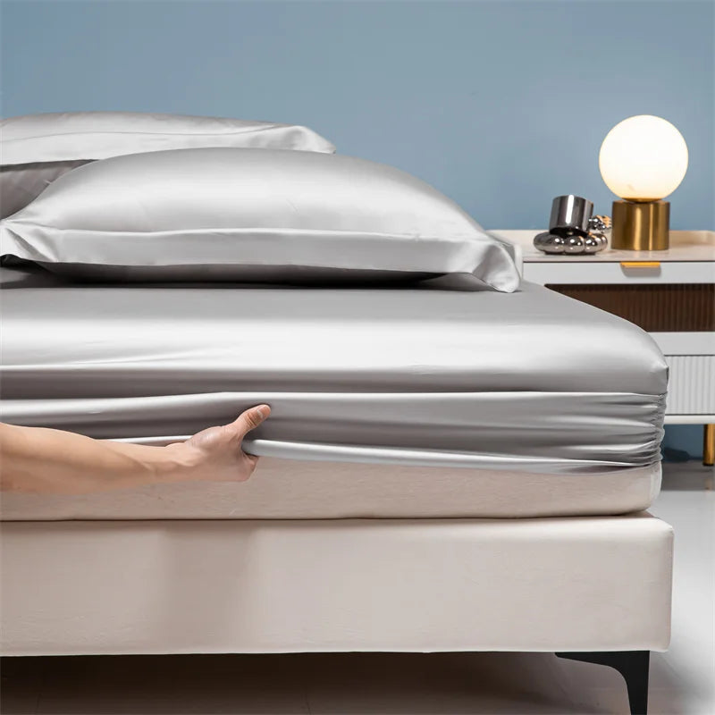 A close-up of a luxury bamboo bedding set featuring silver and beige sheets on a bed.