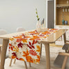 Autumn fall leaves table runner with white pumpkins displayed on a wooden dining table.