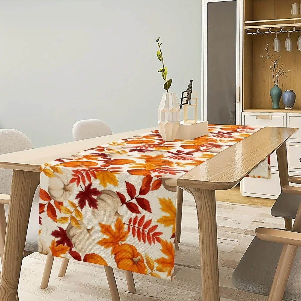 Autumn fall leaves table runner with white pumpkins displayed on a wooden dining table.