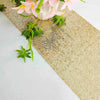 Golden sequin table runner with pink flowers and green foliage on a white surface