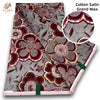 Close-up of Cotton Satin Grand Wax fabric featuring intricate floral patterns in maroon and gold tones.
