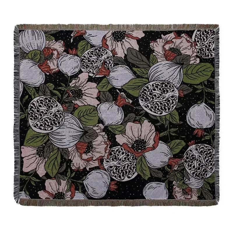 A dark floral pattern throw blanket featuring pink, white, and green botanical designs.