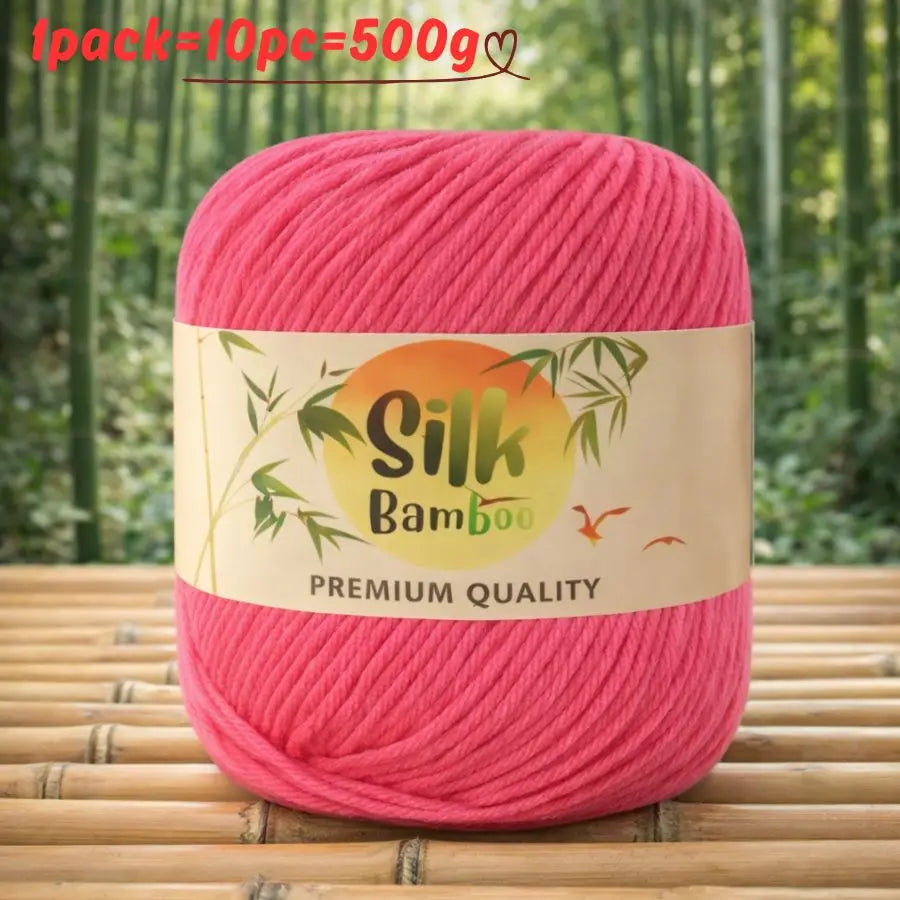 A pink ball of silk bamboo blend yarn with a label indicating premium quality is shown on a bamboo surface.