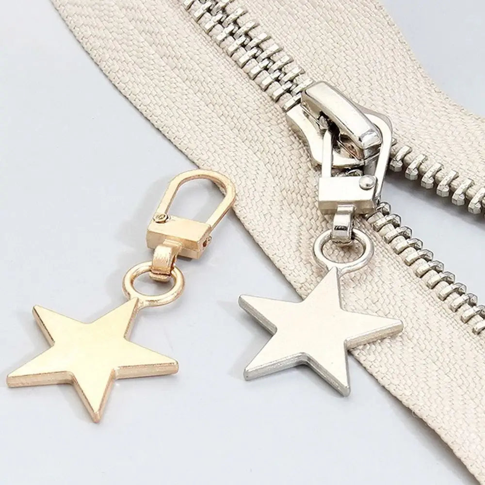 A silver and gold metal zipper pull replacement kit featuring a star charm attached to a beige fabric zipper.