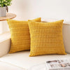 Two mustard yellow knitted throw pillow covers resting on a white surface.