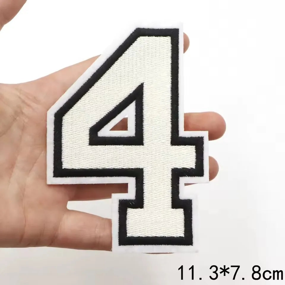 A hand holds a white embroidered letter patch shaped like the number four on a white background.