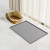 A gray silicone mat is placed on a white floor next to a beige under sink cabinet liner mat.