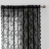 Black lace curtain panel with floral embroidery hanging from a rod.