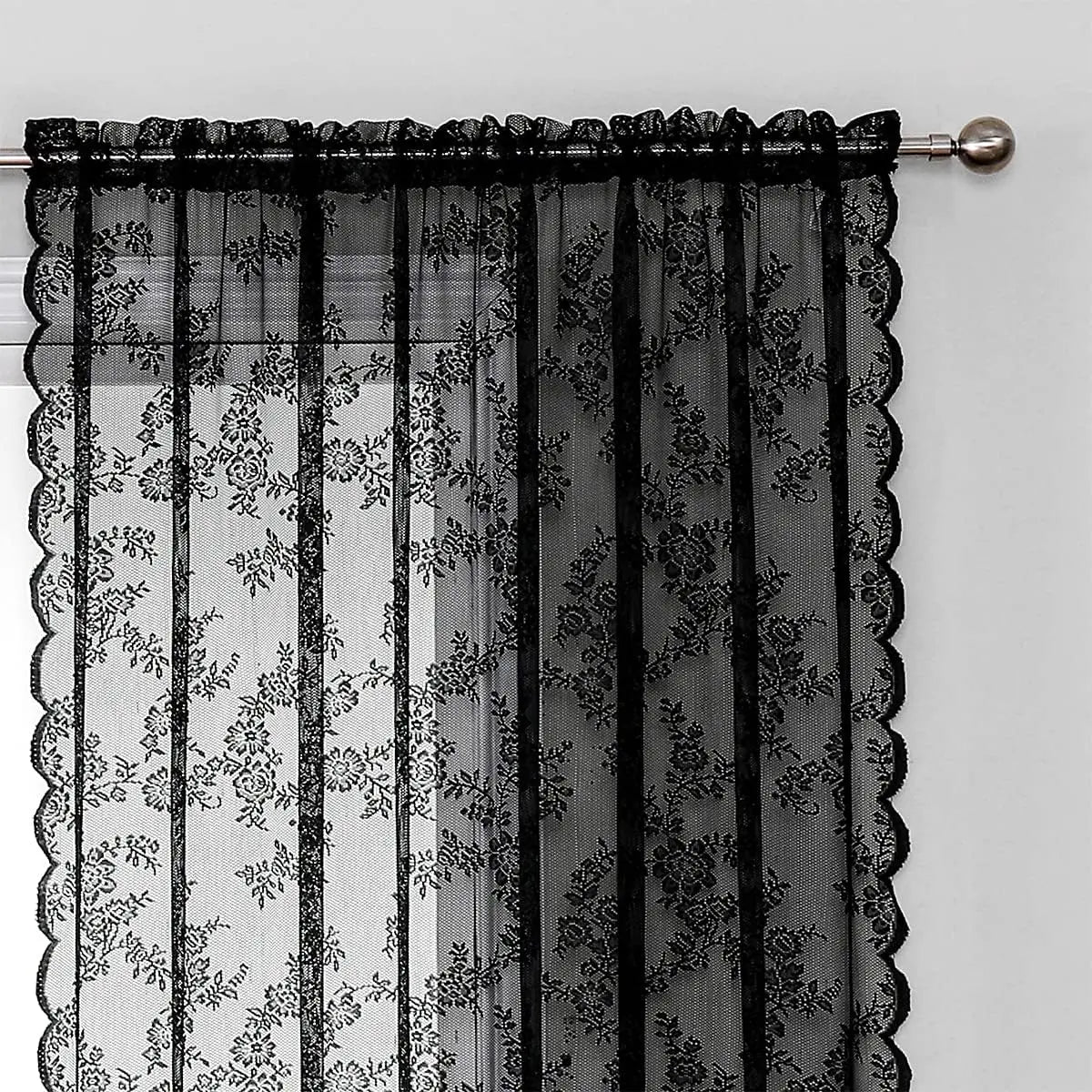 Black lace curtain panel with floral embroidery hanging from a rod.