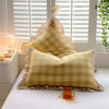 A set of two soft plaid washed cotton pillowcases with ruffled edges resting on a white bed.
