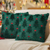 A dark green knitted cushion cover with red holly accents resting on a white blanket.
