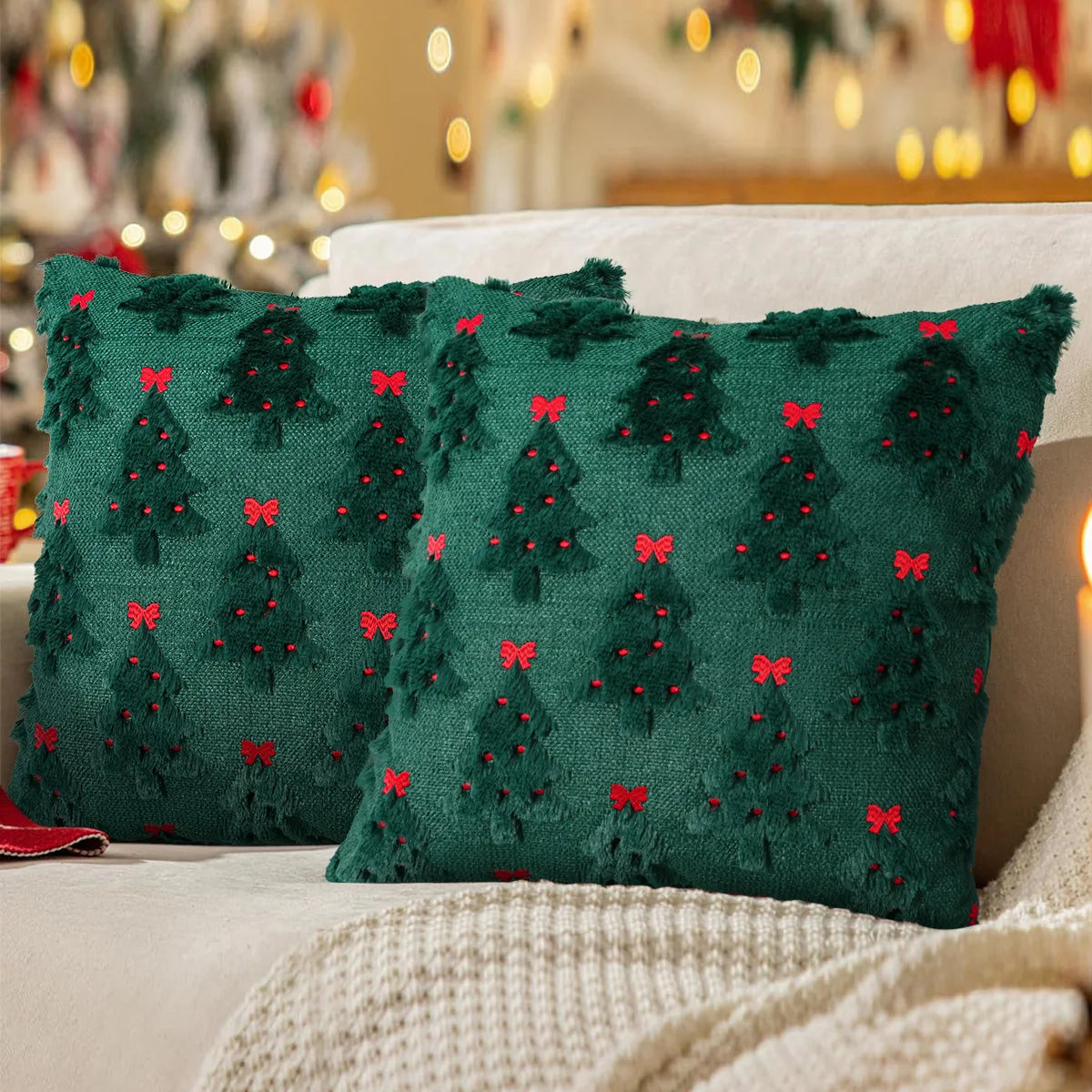 A dark green knitted cushion cover with red holly accents resting on a white blanket.