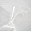 A white duvet cover set with a soft, gathered fabric and a clear plastic tie visible on a white bed.