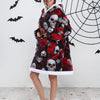 A woman models an oversized patchwork fleece hoodie with skull print against a white wall decorated with black bats and a spi