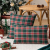 A set of two green and red tartan plaid decorative throw pillow covers resting on a white rug.